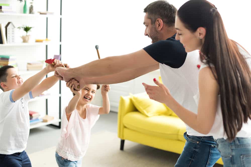 Papá y mamá jugando en casa con niños