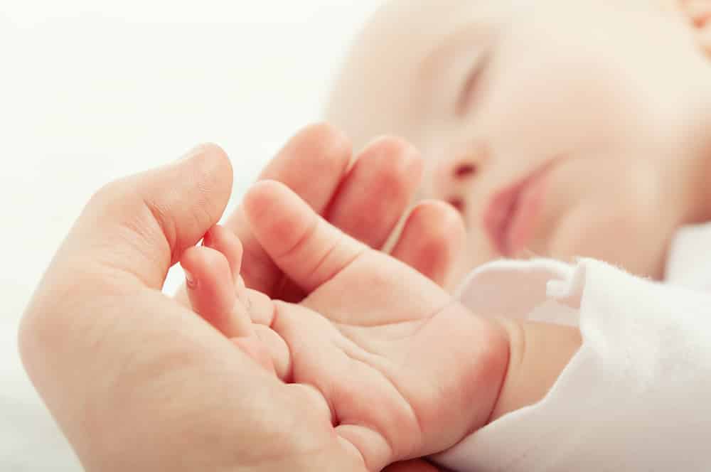 Detalle bebé dormido cogido de la mano